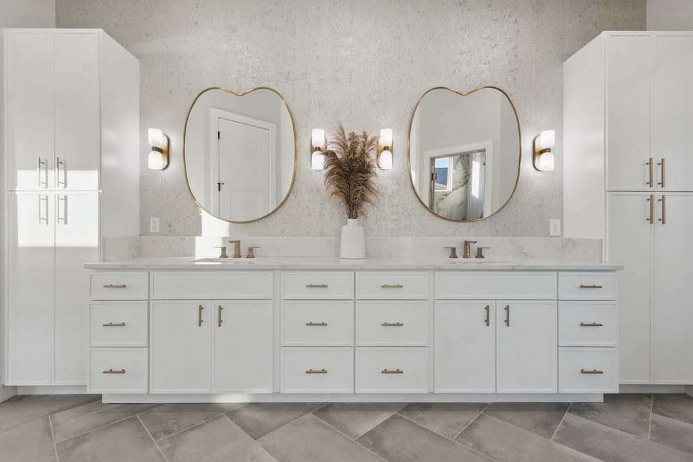 White double vanity with brushed gold hardware, quartz top and two floor-to-ceiling linen tower cabinets